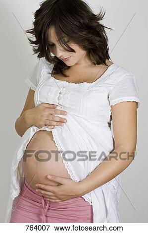 Stock Photo - A pregnant woman cradling her belly. Fotosearch