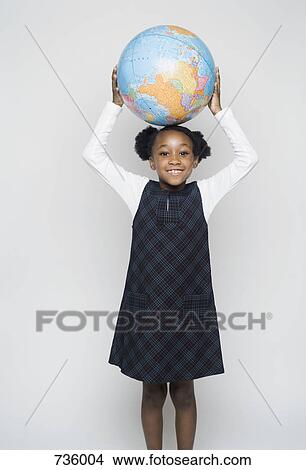 Picture - A schoolgirl holding a globe above her head. Fotosearch