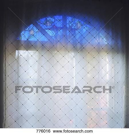 Stock Photograph - A sheet hanging over a stained glass window. Fotosearch