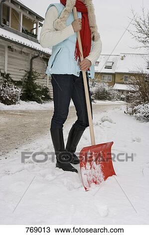 A woman holding a snow shovel, outdoors View Large Photo Image Stock Image - A woman holding a snow shovel, outdoors. Fotosearch