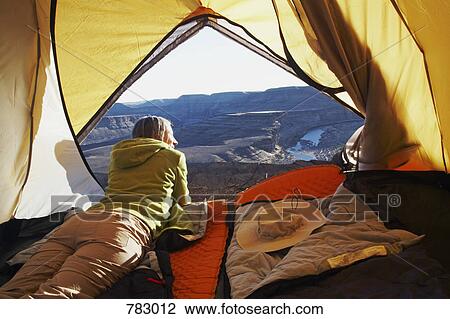 Stock Image - A woman lying in a tent, Horse Shoe Bend, Fish River Canyon, Namibia. Fotosearch