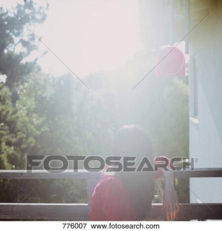 A woman sitting on a balcony View Large Photo Image Stock Photo - A woman sitting on a balcony. Fotosearch