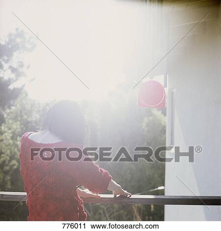 A woman standing on a balcony View Large Photo Image Stock Image - A woman standing on a balcony. Fotosearch