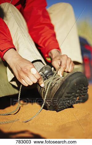 Stock Image - A woman tying hiking boots. Fotosearch