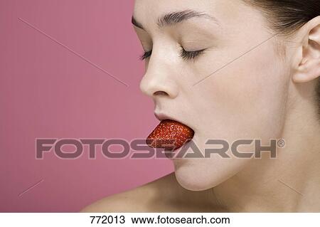 A woman with a strawberry in her mouth View Large Photo Image Stock Image - A woman with a strawberry in her mouth. Fotosearch