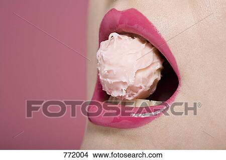 Picture - A woman's mouth with a pink truffle . Fotosearch
