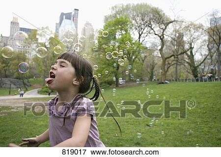 Stock Photo - A young girl catching bubbles in Central Park, New York City. Fotosearch