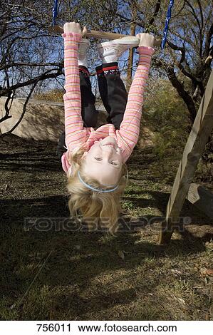 A young girl hanging upside down from a swing View Large Photo Image Stock Image - A young girl hanging upside down from a swing. Fotosearch