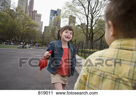 Stock Image - A young girl holding a balloon in Central Park, New York City. Fotosearch