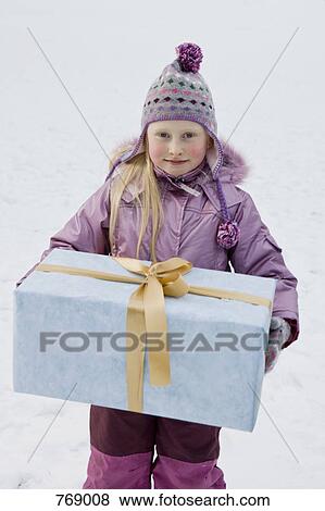 A young girl holding a gift outdoors in the snow View Large Photo Image Stock Photo - A young girl holding a gift outdoors in the snow. Fotosearch