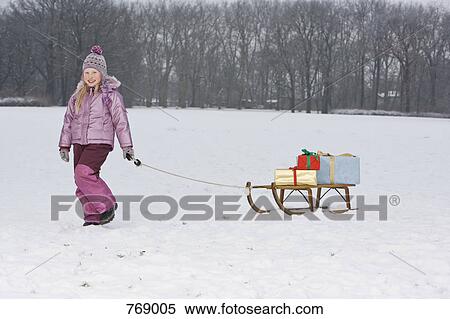 Stock Photography - A young girl pulling a sled with presents on it. Fotosearch