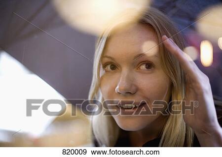 A young woman holding an umbrella and peeking into a window View Large Photo Image Stock Photo - A young woman holding an umbrella and peeking into a window. Fotosearch