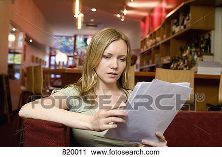 A young woman sitting in a cafe and looking at the menu View Large Photo Image Stock Image - A young woman sitting in a cafe and looking at the menu. Fotosearch