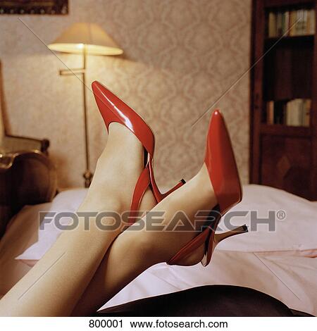 Stock Image - Detail of a woman with her feet up and wearing high heel shoes. Fotosearch