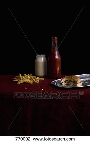 Stock Image - Partially eaten cheeseburger and French Fries, still life. Fotosearch