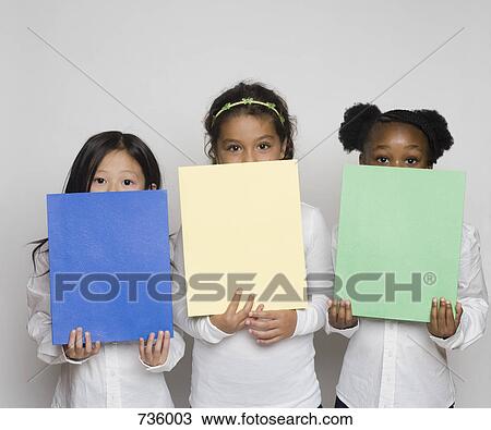Three girls holding up multi colored paper View Large Photo Image Stock Image - Three girls holding up multi colored paper. Fotosearch