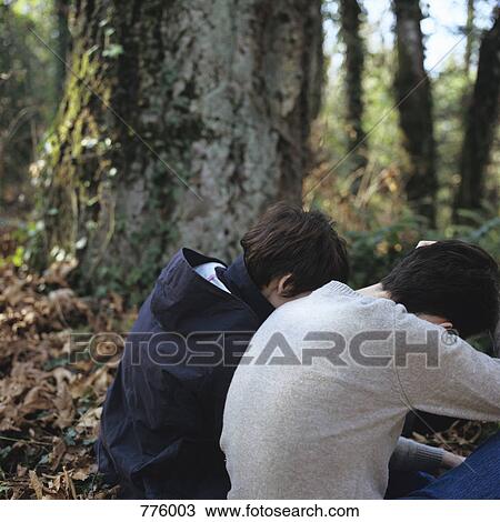 Two people sitting hunched over in a forest View Large Photo Image Stock Image - Two people sitting hunched over in a forest. Fotosearch