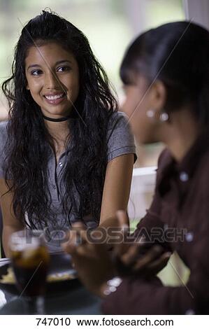 Stock Image - Two young women sitting at a cafe. Fotosearch