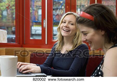 Stock Image - Two young women sitting in a cafe together. Fotosearch