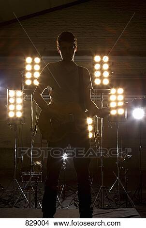 Picture - A rock musician playing a guitar on a stage. Fotosearch
