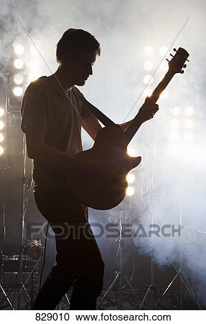 A rock musician playing a guitar on a stage View Large Photo Image Stock Image - A rock musician playing a guitar on a stage. Fotosearch