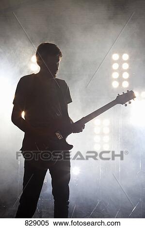 Stock Photography - A rock musician playing a guitar on a stage. Fotosearch