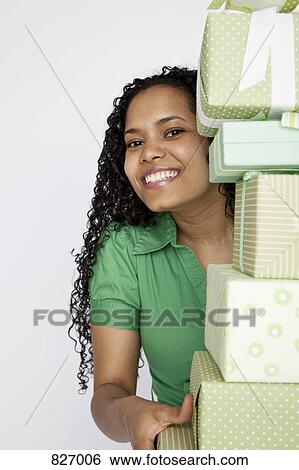 A woman peeking from behind a stack of presents View Large Photo Image Stock Photograph - A woman peeking from behind a stack of presents. Fotosearch