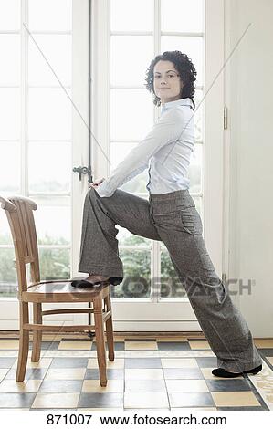 A businesswoman stretching against a chair View Large Photo Image Stock Photo - A businesswoman stretching against a chair. Fotosearch