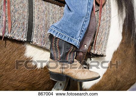 A cowboy boot on a child's leg horseback riding, side view, close-up View Large Photo Image Picture - A cowboy boot on a child's leg horseback riding, side view, close-up. Fotosearch