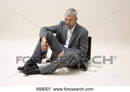 A depressed businessman holding a bottle of wine View Large Photo Image Stock Photo - A depressed businessman holding a bottle of wine. Fotosearch