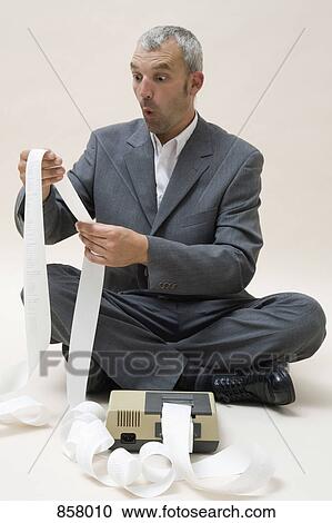 A shocked business man looking at printed receipts from a calculator View Large Photo Image Stock Image - A shocked business man looking at printed receipts from a calculator. Fotosearch