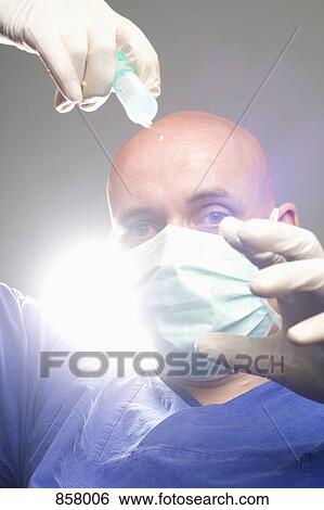 A surgeon holding a syringe View Large Photo Image Stock Photograph - A surgeon holding a syringe. Fotosearch