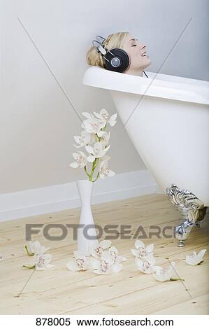 A woman enjoying a bath in a clawfoot tub, listening to headphones and singing along View Large Photo Image Stock Photography - A woman enjoying a bath in a clawfoot tub, listening to headphones and singing along. Fotosearch