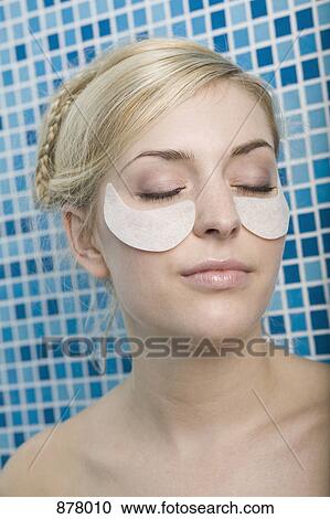 Stock Image - A woman with cotton pads on her cheekbones. Fotosearch
