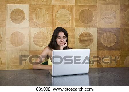 A young woman sitting at a marble table using a laptop View Large Photo Image Stock Image - A young woman sitting at a marble table using a laptop. Fotosearch
