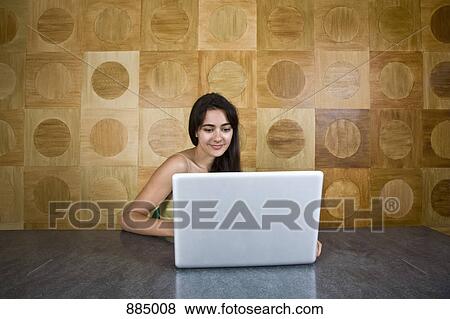 A young woman sitting at a marble table using a laptop View Large Photo Image Stock Photo - A young woman sitting at a marble table using a laptop. Fotosearch