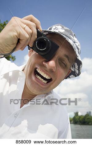 An ecstatic man taking a photo with a digital camera View Large Photo Image Stock Photo - An ecstatic man taking a photo with a digital camera. Fotosearch