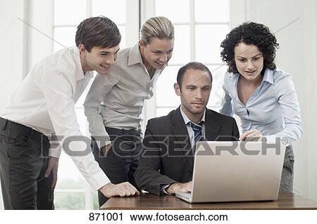 Business colleagues gathered around a laptop View Large Photo Image Stock Image - Business colleagues gathered around a laptop. Fotosearch