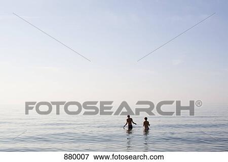 Two people standing in the sea View Large Photo Image Stock Photo - Two people standing in the sea. Fotosearch
