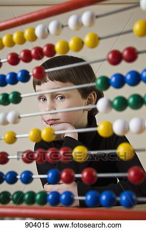 Stock Photography - A boy looking through an abacus. Fotosearch