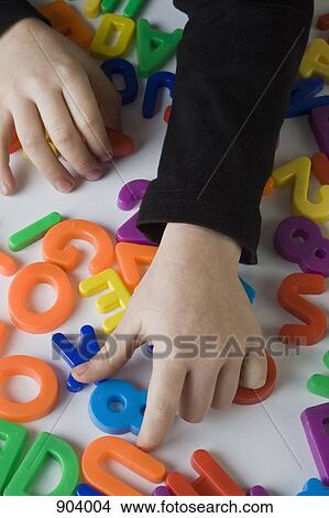 Picture - A boy playing with letter magnets, detail of hands. Fotosearch