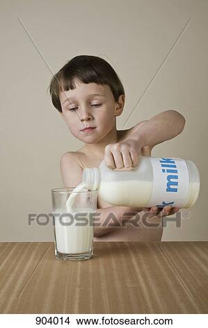 Picture - A boy pouring milk into a glass. Fotosearch
