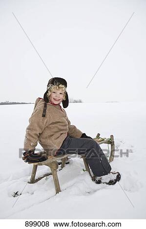 A boy sitting on a sled View Large Photo Image Stock Photo - A boy sitting on a sled. Fotosearch