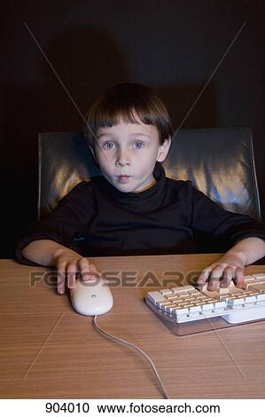 Stock Image - A boy using a computer mouse and keyboard. Fotosearch