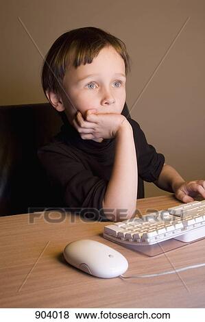 Stock Photo - A boy using a computer mouse and keyboard. Fotosearch