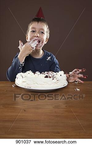 A boy wearing a party hat eating pie with his hands, studio shot View Large Photo Image Stock Photo - A boy wearing a party hat eating pie with his hands, studio shot. Fotosearch