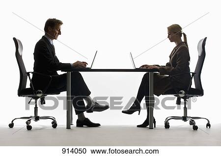 A businesswoman and businessman working on laptops, face to face View Large Photo Image Stock Image - A businesswoman and businessman working on laptops, face to face. Fotosearch