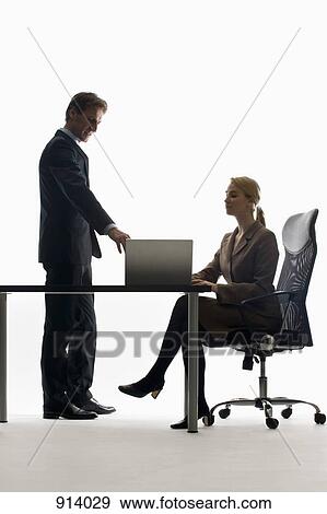 Stock Photo - A businesswoman and businessman working together with a laptop. Fotosearch