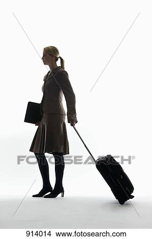 A businesswoman pulling a wheeled carry on and holding a portfolio View Large Photo Image Picture - A businesswoman pulling a wheeled carry on and holding a portfolio. Fotosearch