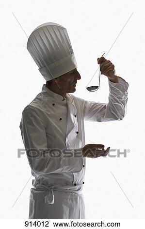 Stock Image - A chef holding a ladle up to his mouth, portrait. Fotosearch